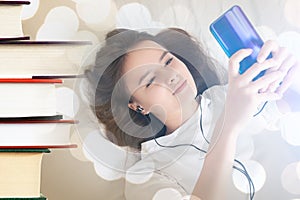 Audio book,girl with a phone in headphones listens to literature among book volumes