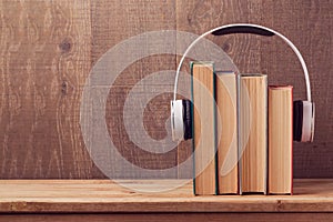 Audio books concept with old books and headphones over wooden background