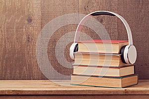Audio books concept with stack of old book and headphones on wooden table photo