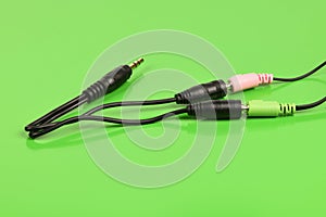 Audio cable splitter, stereo male to two female stereo audio jack 3,5 mm, isolated on a green background. Extreme closeup