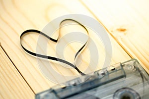 Audio cassette with magnetic tape in shape of heart on wood back
