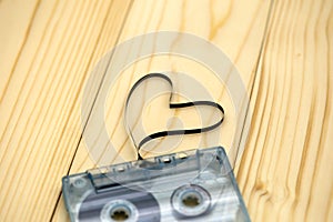 Audio cassette with magnetic tape in shape of heart on wood back