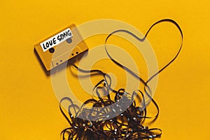 Audio Cassette Tape With The Inscription Love Song And Heart On A Yellow Background. Retro Technology Romance Concept