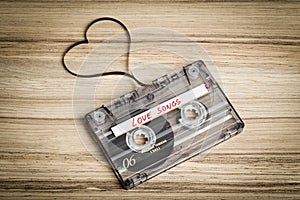 Audio cassette tape on wooden backgound. Film shaping heart photo