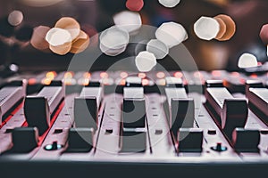 Audio console mixer close up with faders up, bokeh background