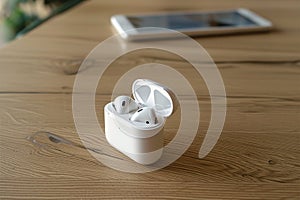 Audio convenience White wireless earphones on table, technology concept