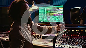 Audio engineer working with mixing console and motorized faders