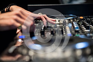 Audio mixer console and professional sound mixing. A female black hand is adjusting audio mixer with buttons and sliders.