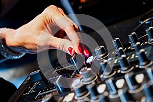 Audio mixer console and professional sound mixing. A hand is adjusting audio mixer with buttons and sliders. Mixer console for mus