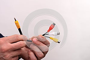 Audio video cable RCA jack in a man's hands on a white background.