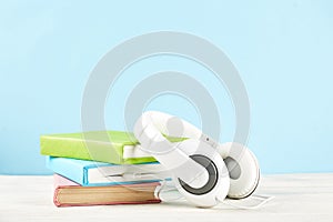 Audio vs. paper book concept. Reading versus listening. Books and headphones on table