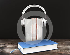 Audiobook concept with headphones on hardcover books against dark background