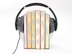 Audiobooks concept. Headphones put over book and white background