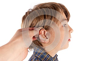 Audiologis inserting a hearing aid in a young boy patient`s ear.