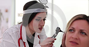 Audiologist examines patient ear using otoscope