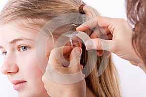 Audiologist inserting a hearing aid