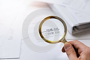 Audit concept - auditor checking bills with magnifying glass