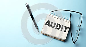 AUDIT text written on a notepad on the blue background