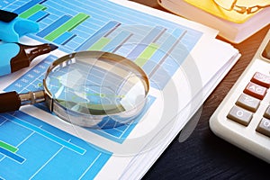 Auditing. Magnifying glass on financial documents with graphs. Audit.