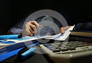 Auditor checks financial report with magnifying glass. Internal audit and business analysis photo