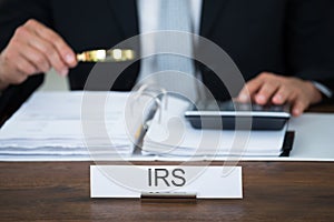 Auditor Examining Documents With Magnifying Glass At Table