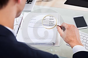 Auditor examining invoice with magnifier