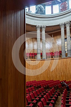 auditorium with red chairs, roman columns, wooden walls, latin america