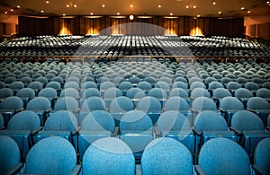 Auditorium with rows of blue seats with railing in back