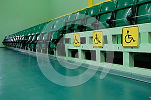 Auditorium with rows of green seating. Disabled areas are marked with special yellow signs
