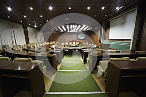 Auditorium with table and armchairs around it.