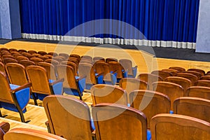 The auditorium in the theater. Blue curtain on the stage. Blue-brown chair. Room without people