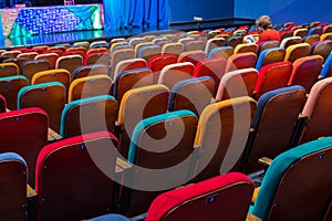 The auditorium in the theater. Multicolored spectator chairs. One person in the audience