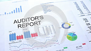 Auditors report lying on table, graphs charts and diagrams, official document