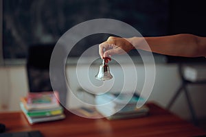 Hand of a Teacher Ringing the Bell to Start the Class
