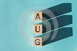 AUG text made of wooden cube on light blue background