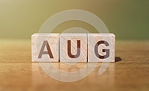 AUG word written on wooden blocks on wooden table. Concept for your design