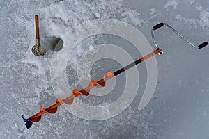 Auger and skimmer, tools for ice fishing.