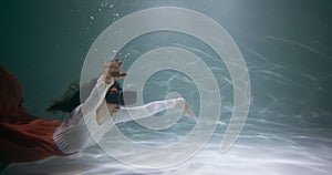 Augmented reality concept. Attractive mixed race woman using AR headset glasses floating deep under water slow motion.