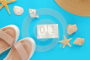 August 01. Wooden calendar on a blue background with summer accessories, top view