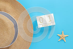August 01. Wooden calendar on a blue background with summer accessories, top view