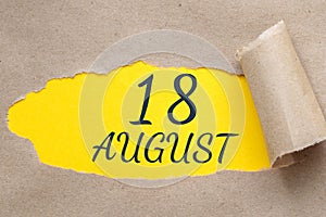 august 18. 18th day of the month, calendar date.Hole in paper with edges torn off. Yellow background is visible through