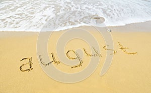 August - written in sand on beach texture