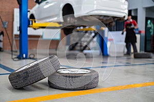 Auomobile repair, Used car tires on epoxy floor in auto workshop, Vehicle raised on lift at maintenance station. Check the