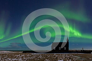 Aurora borealis above the church in Iceland. Green northern lights. Starry sky with polar lights.