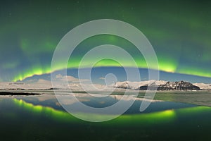 Aurora borealis above the sea. Jokulsarlon glacier lagoon, Iceland. Green northern lights. Starry sky with polar lights.