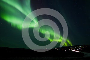 Aurora Borealis arc over hill terrain