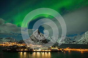 Aurora borealis dancing on mountain in fishing village at Reine and Sakrisoy, Lofoten, Norway Visiting the Lofoten Islands.