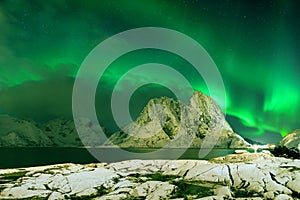 Aurora borealis dancing on mountain in fishing village at Reine and Sakrisoy, Lofoten, Norway Visiting the Lofoten Islands.