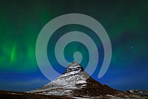 Aurora Borealis from Iceland. Beautiful green Northern Lights on the dark blue night sky with peak with snow, Kirkjufell