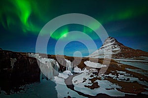 Aurora Borealis from Iceland. Beautiful green Northern Lights on the dark blue night sky with peak with snow, Kirkjufell, Iceland.